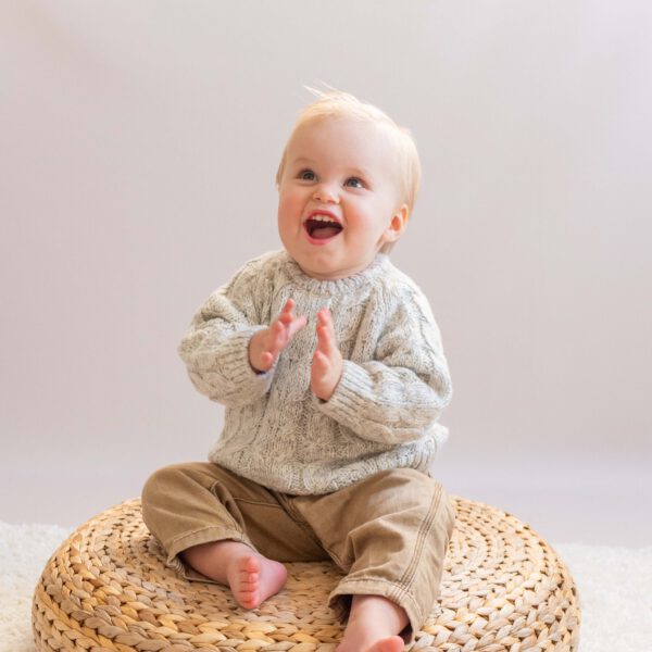 Een vrolijke baby straalt op de foto, vol vreugde en verwondering tijdens de fotoshoot in de studio bij van Lente fotografie in Spijkenisse.