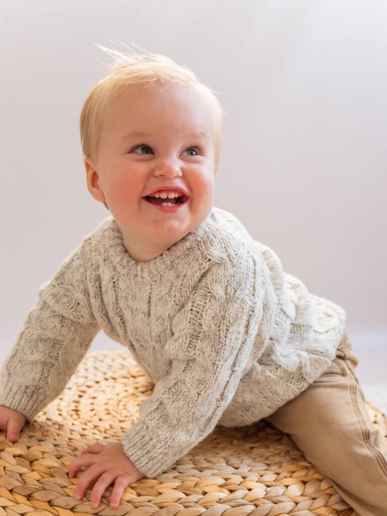 Een vrolijke baby straalt op de foto, vol vreugde en verwondering tijdens de fotoshoot in de studio bij van Lente fotografie in Spijkenisse.