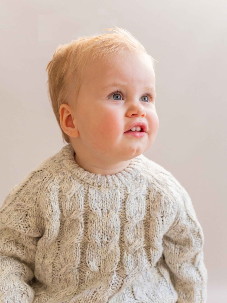 Een vrolijke baby straalt op de foto, vol vreugde en verwondering tijdens de fotoshoot in de studio bij van Lente fotografie in Spijkenisse.